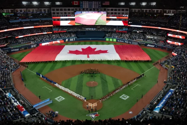 Fans and players stand for the Canadian national anthem ahead of the Toronto Blue Jays home opener against the Baltimore Orioles, in Toronto on Thursday, March 27, 2025